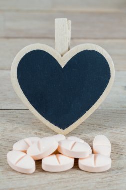 Boş kalp şekli tahtaya tahta arka plan ile pembe hap