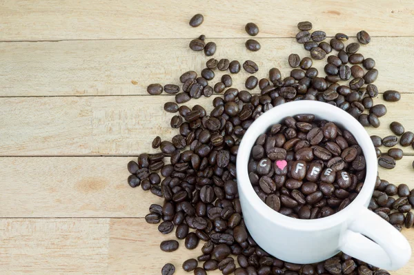 Granos de café en taza blanca y fondo de madera — Foto de Stock