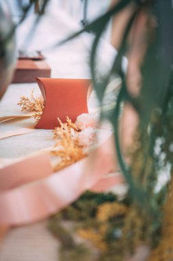 Düğün töreni için turuncu hediye kutusu maketi. Artistik ön plan bulanıklığı, yeşil yapraklar ve yumuşak arka plan. Lüks markalaşma için şık ve rüya gibi bir atmosfer..