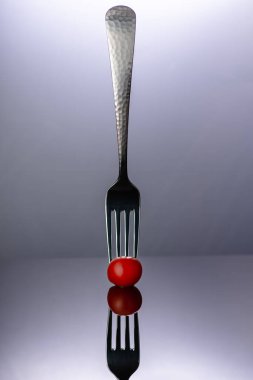 Mezuniyet geçmişine ve yansıtıcı yüzeyine domates delen çatal..