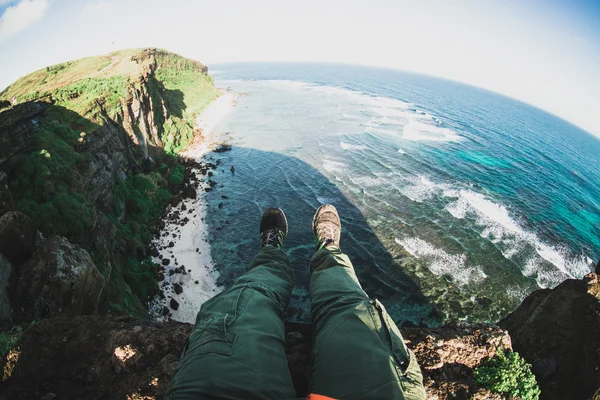 male legs hanging over cliff edge