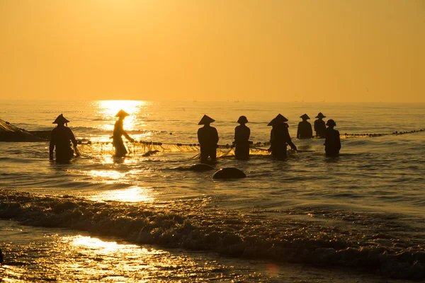 Fiskare på stranden i soluppgång — Stockfoto