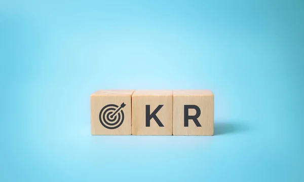 OKR metni (Hedefler, Anahtar ve Sonuçlar) mavi arkaplanda tahta küp bloklar. İş hedefi ve iş ve performans. Hedefe odaklan. Esnek yönetimle iş büyümesi elde et