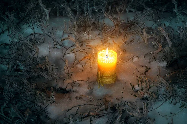 Candela ardente di Natale in piedi sulla neve ghiacciata circondata da erba ghiacciata. Candela solitaria in inverno fuori di notte. — Foto Stock