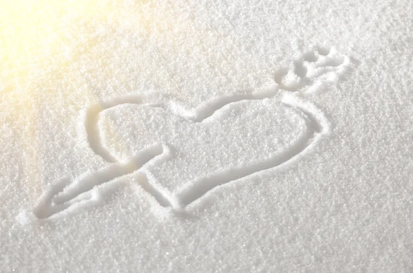 Big heart pierced by an arrow of love drawn in the snow in the winter