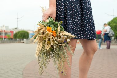 Young woman holds motley grass bouquet during Macovei celebratio clipart