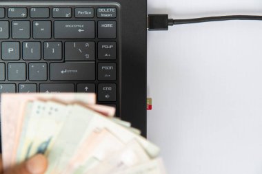 Üst görünüm siyah klavyenin elinde banknot var ve beyaz arkaplandaki bilgisayara takılı bir hafıza kartında metin için boşluk var. iş çevrimiçi konsept, gelecek nesil online para kazan.