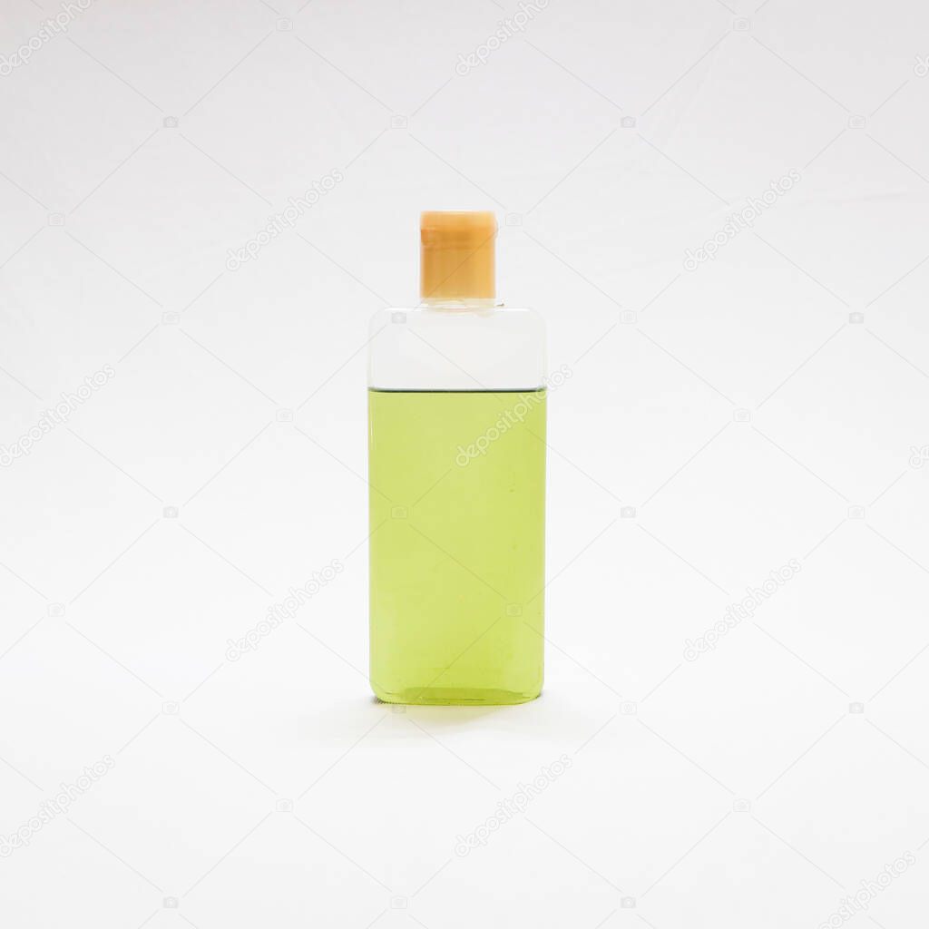 green natural ayurvedic hair oil in a transparent plastic bottle isolated in a white background