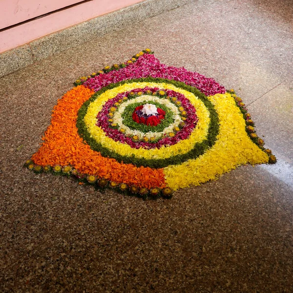 Pembe, sarı ve turuncu çiçekli pookalam adı verilen renkli çiçek aranjmanı Hint festivali onam ile bağlantılı.