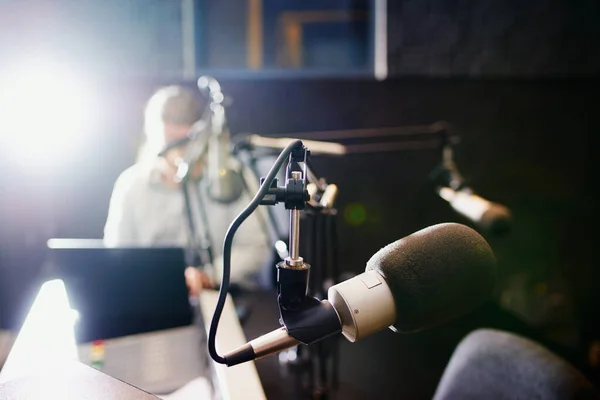 stock image Shot of a microphone in a recording studio with the presenter blurred in the background