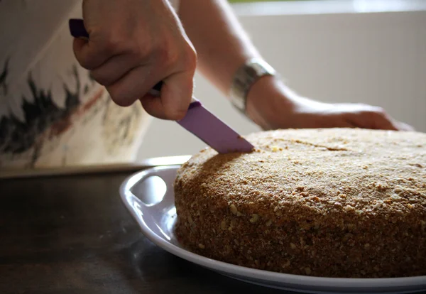 Femme coupe gâteau au miel avec un couteau — Photo