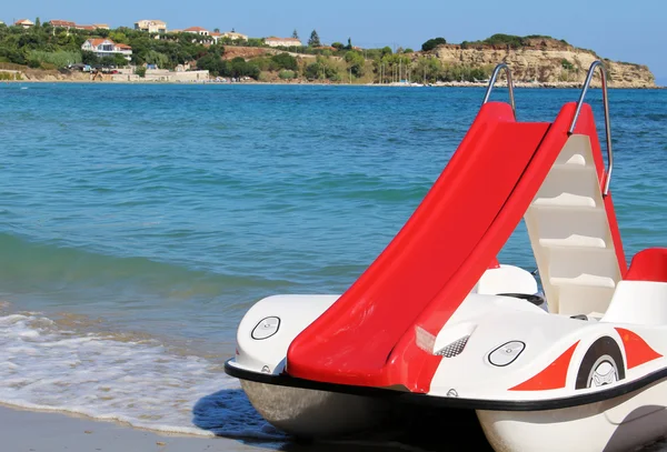 Red pedalo boat with slide on the beach Stock Image