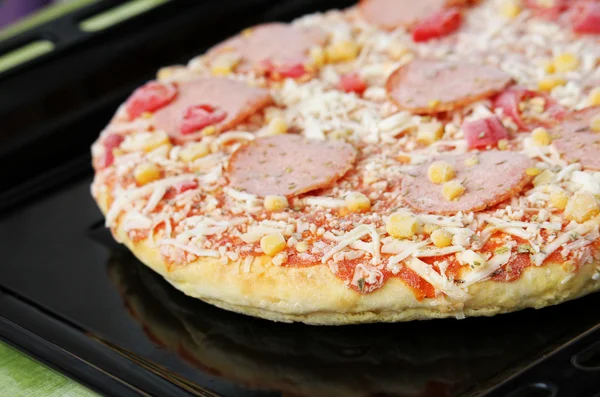 Frozen pizza with salami, cheese, corn and pepper Stock Picture