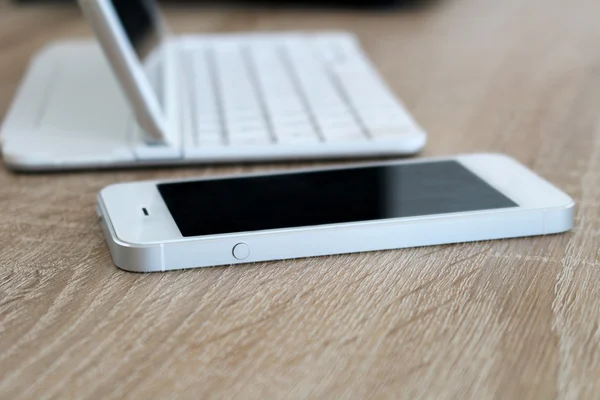 White cellphone and tablet with keyboard on table Stock Photo