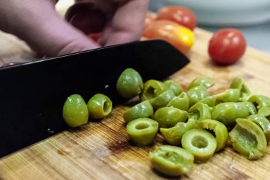Adım adım ev yapımı salata resepsiyonu. Yaklaştın sayılır, adam salata hazırlıyor ve tahta üzerinde yeşil zeytin kesiyor.