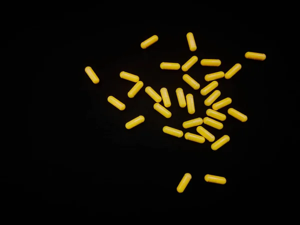 Μια Χούφτα Κίτρινες Κάψουλες Είναι Διάσπαρτες Μαύρο Φόντο Αντίγραφο Χώρου — Φωτογραφία Αρχείου