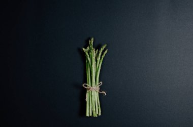 Siyah bir arka planda sicim yayıyla bağlanmış bir grup yeşil kuşkonmaz..