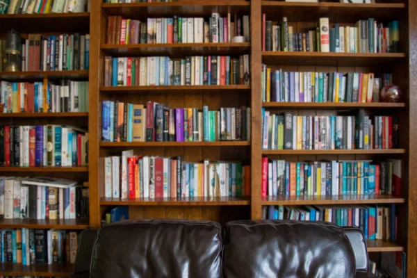 Wooden bookcase filled with blurred books in a UK home setting — Stock Photo, Image