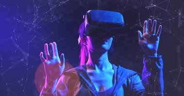 Siyah arka planda sanal gerçeklik gözlüklü genç bir kadın.