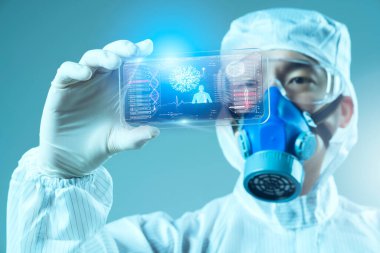 Koruyucu giyimde olan bilim adamı hologram akıllı telefon kullanıyor.