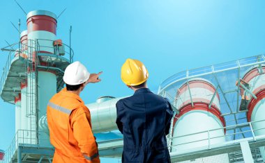 Fabrika borularıyla kask takan mühendisler.