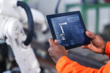 Üniformalı işçilerin arka planda robotlu tablet bilgisayar kullanırken çekilmiş görüntüleri.