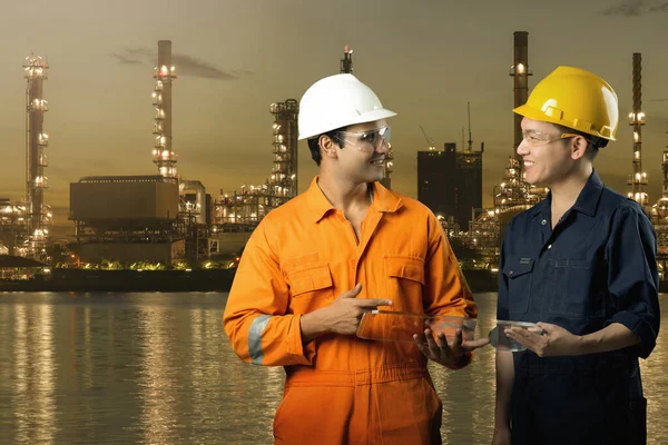 two engineers with night illuminated factory on background