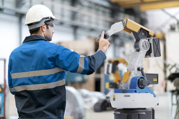 engineer wearing helmet working with robot in factory interior