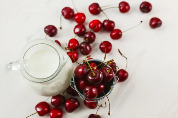 Fresh cherries with jug of milk — Stock Photo, Image