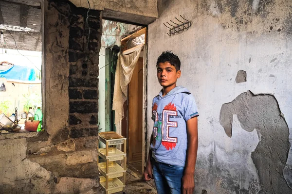 Ten chlapec ukazuje poškozený dům, v němž musel žít kvůli válce — Stock fotografie