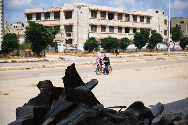People walking down the street destroyed after fighting in Homs