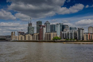 Canary Rıhtımı 'nda bulutlu bir gökyüzünün altında sakin bir Thames nehrinin büyüleyici manzarası..