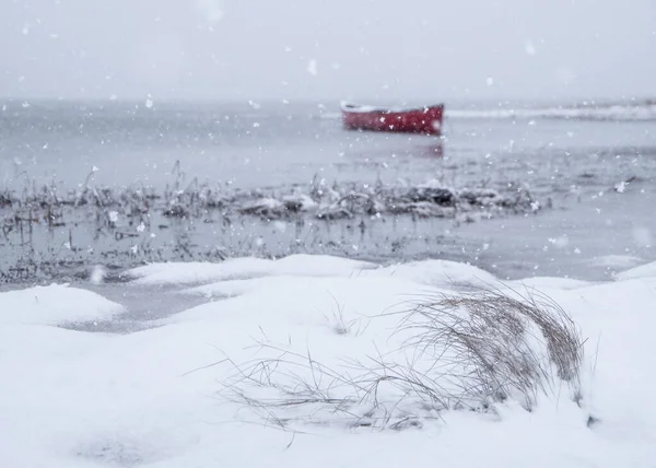 Dreamy snowfall over a red canoe on the coast of Maine