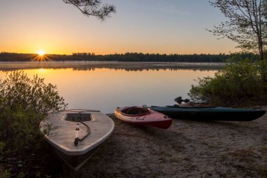 Gündoğumu yansıması ve güneş Maine Gölü 'nde yelkenli ve kanoların üzerinde parıldıyor.