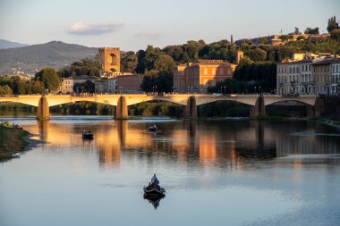 Ponte alle Grazie, bridge in Florence, Italy with boats on the river Arno and the Porta San Niccol in the background 