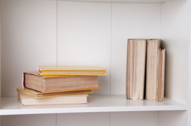 Ahşap kitaplık üzerinde ciltli kitap yığını. 