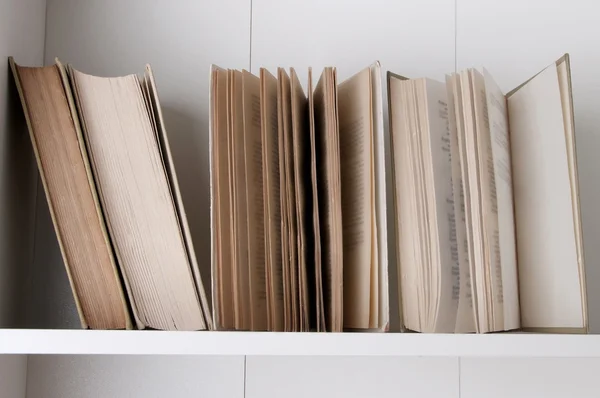 Open book, stack of hardback books on bookshelf. — Stock Photo, Image