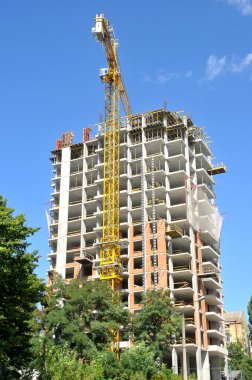 Mavi gökyüzüne karşı inşaat halindeki vinç ve bina