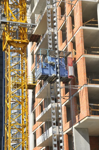 Building site with high-rise block under construction in an urban environment dominated by a large industrial crane silhouette.