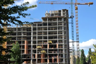 Çalışma yer yüksek bina yapım aşamasında ve vinçler mavi gökyüzü altında. Homes inşaat altında