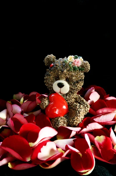Petit ours avec cœur au milieu des pétales de rose — Photo