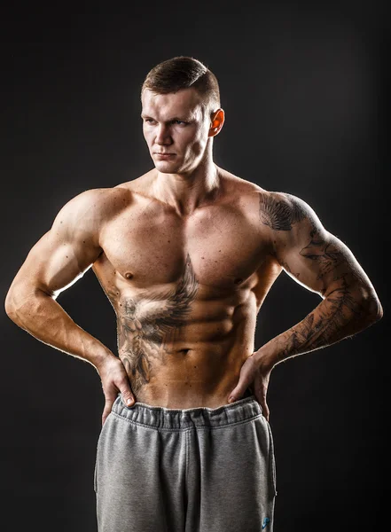Un tipo musculoso con tatuaje. Aislado sobre fondo oscuro — Foto de Stock
