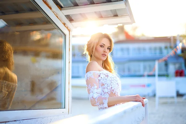 Menina bonita com cabelo loiro em vestido de renda elegante posando ao lado de um mar — Fotografia de Stock