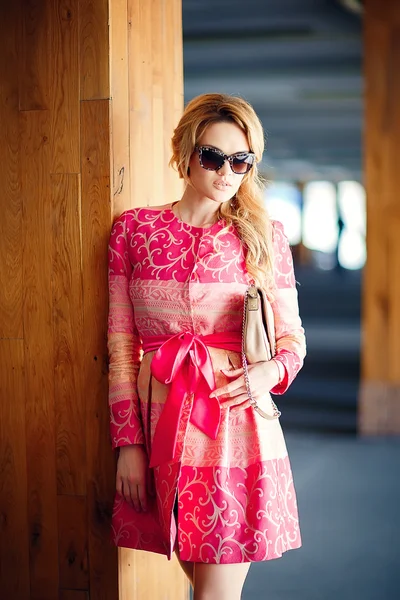 Foto de moda de menina bonita com cabelo loiro vestindo vestido rosa luxuoso, saco no estacionamento subterrâneo . — Fotografia de Stock