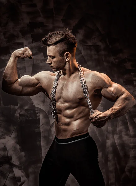 Der perfekte männliche Körper - genial Bodybuilder posiert. eine Kette halten — Stockfoto