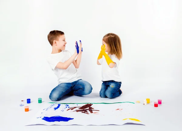 Duas crianças bonitas amigos menino e menina estão desenhando quadros por tintas. Mostrando as mãos em tinta, sckream, rugido, feliz . — Fotografia de Stock