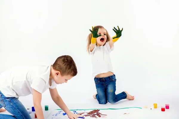 Duas crianças bonitas amigos menino e menina estão desenhando quadros por tintas. Mostrando as mãos em tinta, sckream, rugido, feliz . — Fotografia de Stock