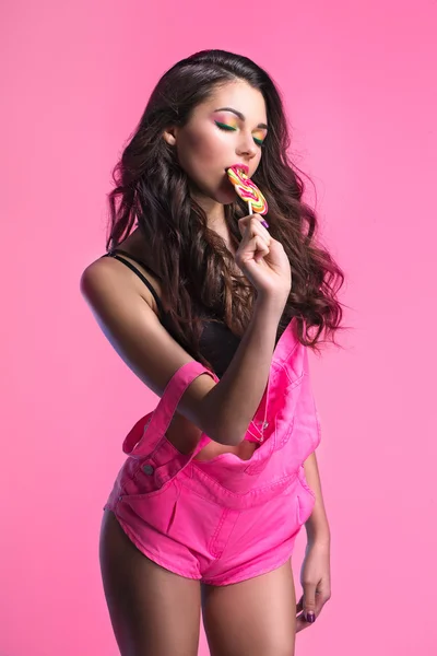 Sexy jeune fille en combinaison rose tenant sucette . — Photo