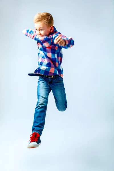 Jumping little boy in the colorful plaid shirt, blue jeans, gumshoes. Isolated. — Stock Fotó