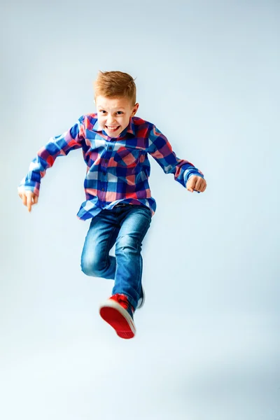 Jumping little boy in the colorful plaid shirt, blue jeans, gumshoes. Isolated. — Φωτογραφία Αρχείου
